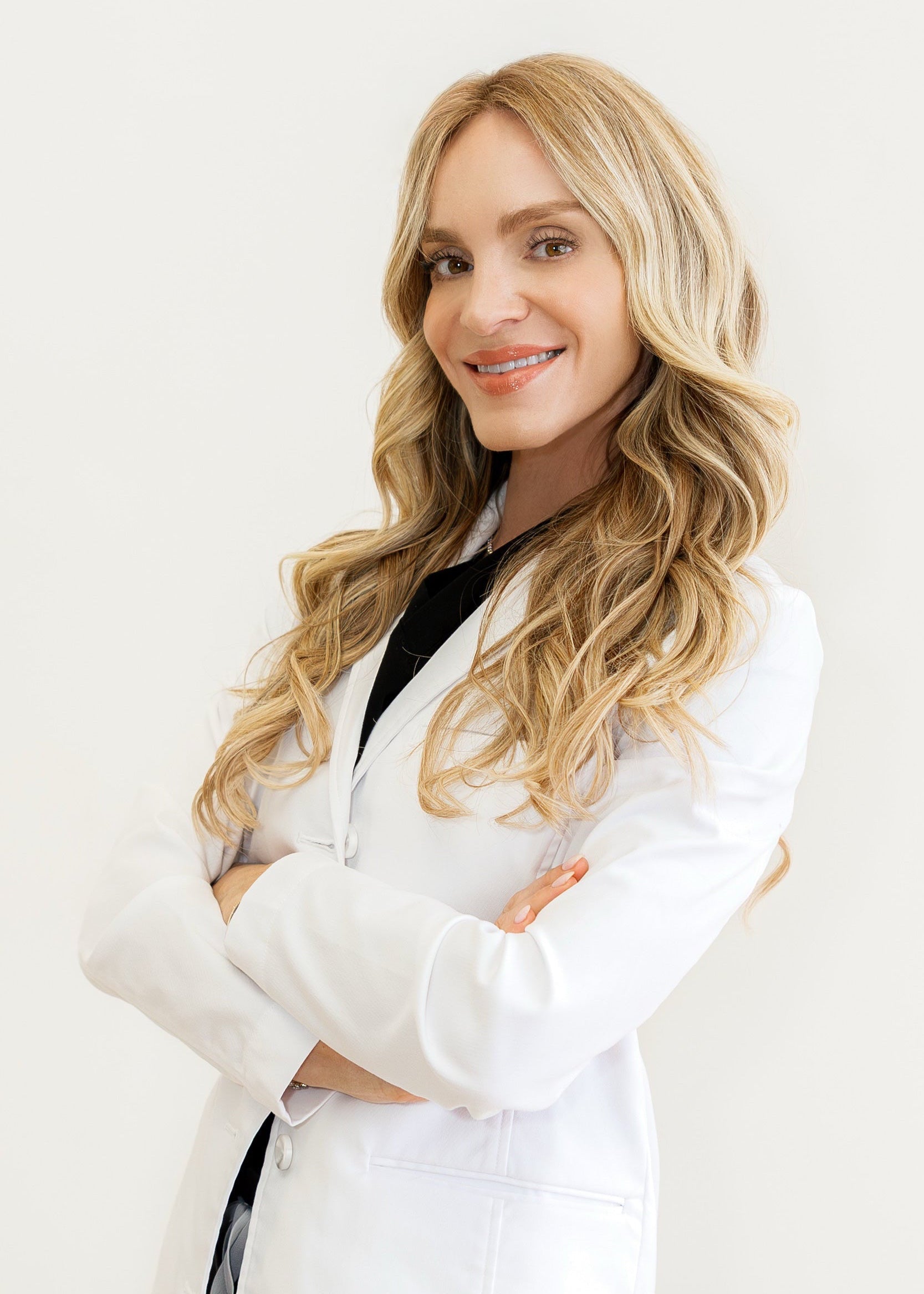 Woman in a white lab coat with long blonde hair on a plain background