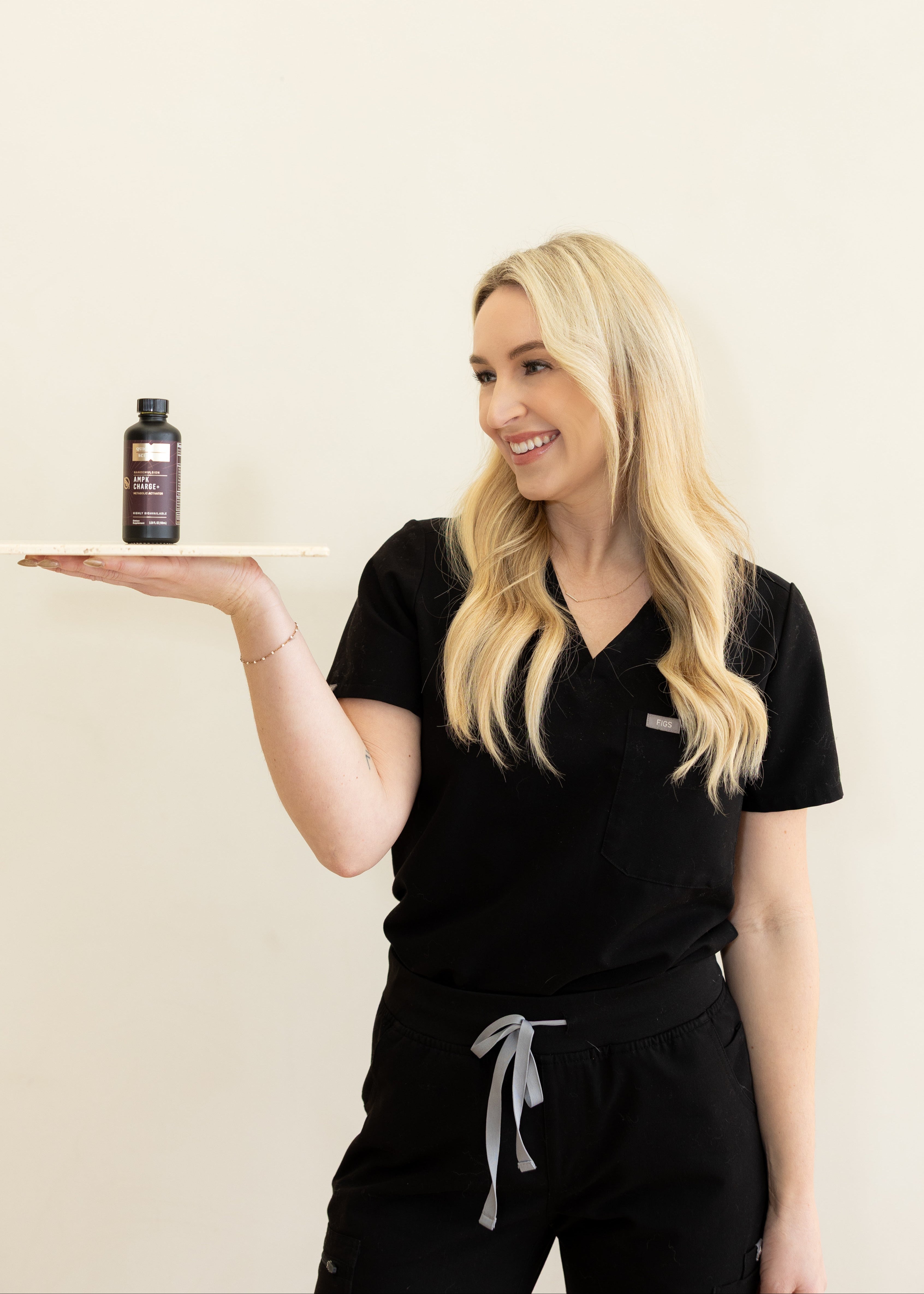 Woman holding a small bottle on a white surface