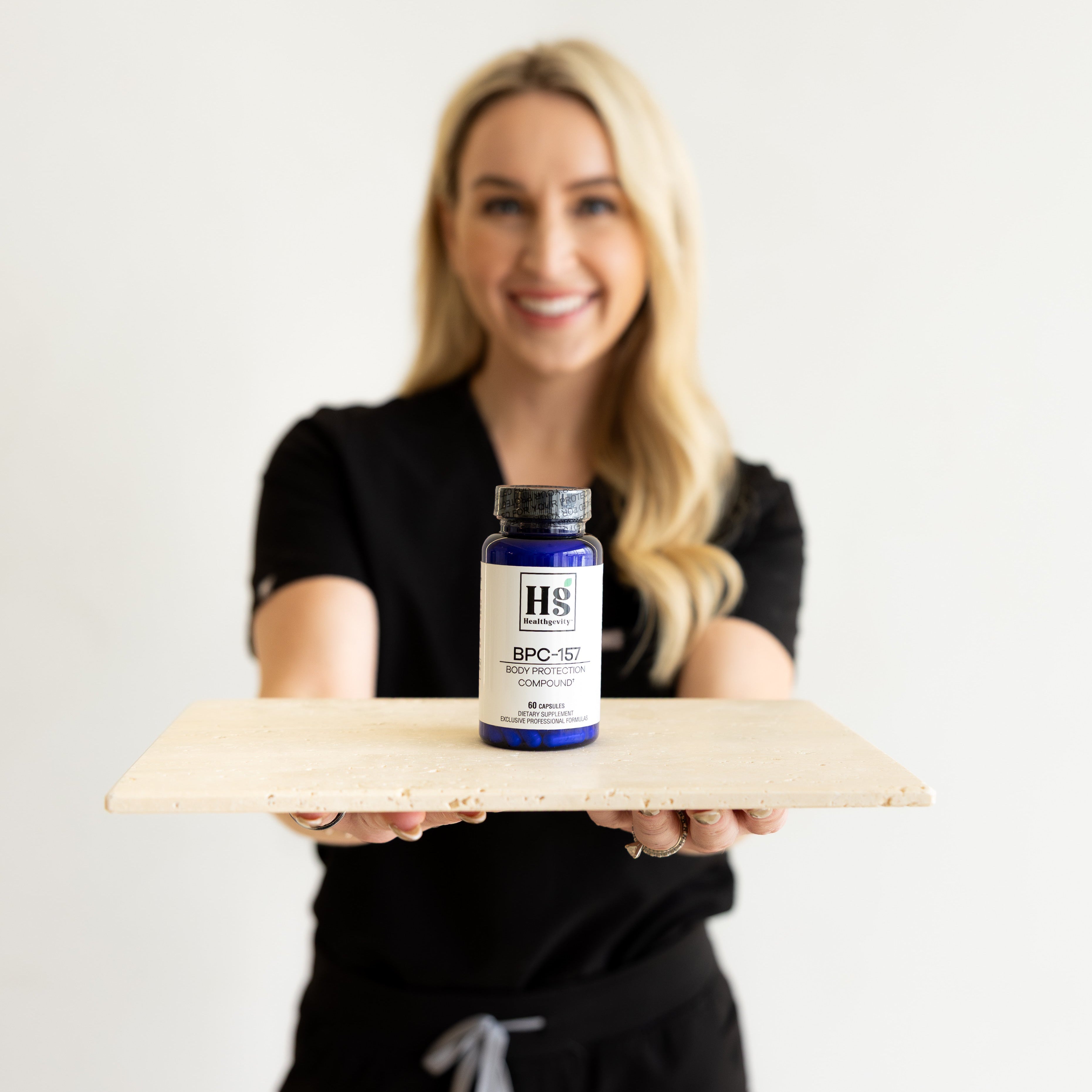 Person holding a bottle of HS Supplements on a white background