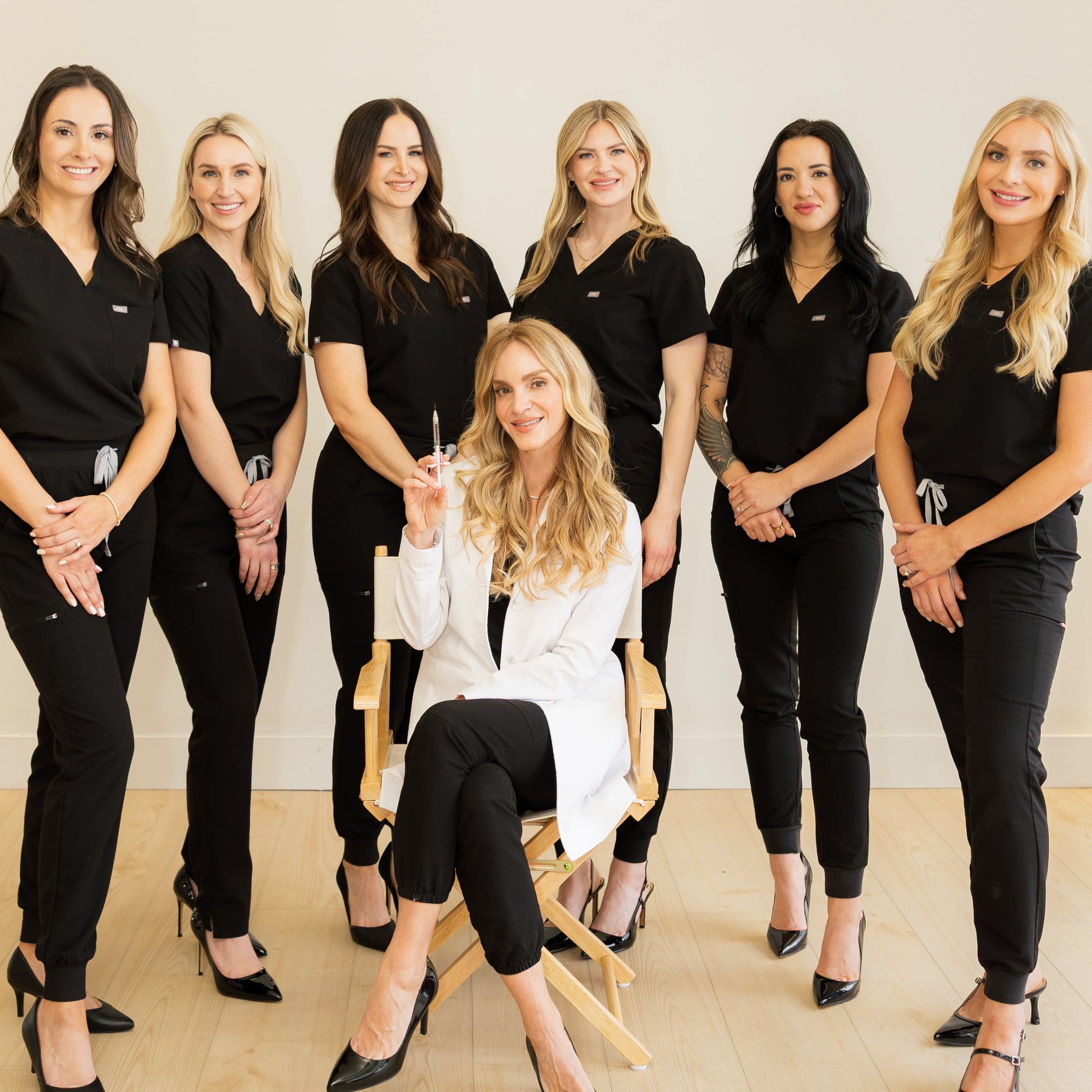 Group of women in black uniforms posing for a photo with one woman in a white chair.